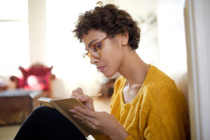 woman with glasses sitting and journaling