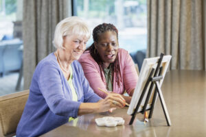 senior lady painting with caregiver