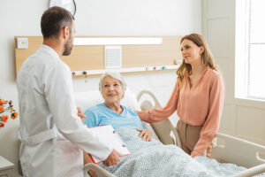 Senior woman in bed during a hospital stay, talking with her adult daughter and doctor