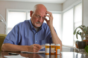 An older man reviews medication bottles to help mitigate his risk of falls.