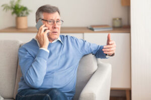 A senior man who understands the risks of AI-driven imposter scams speaks to someone on his cell phone.